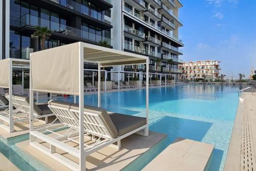 a swimming pool with two lounge chairs and a building at Free housekeeping visits during your stay - StayShort - Luxury 2BR with Private Pool & Skyline Terrace JVC in Dubai