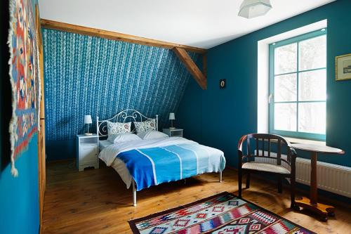 a bedroom with blue walls and a bed and a chair at Stara Szkoła Browina in Browina