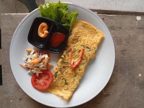 a plate of food with a omelet and a salad at Homies Place Tetebatu in Tetebatu