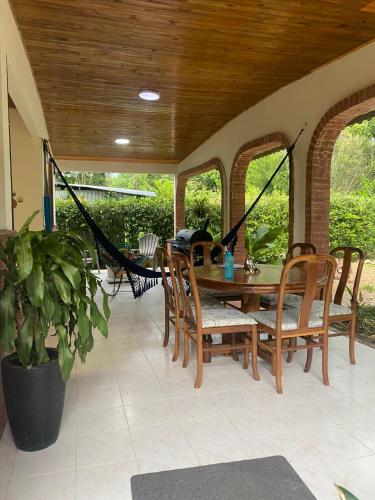 Un porche con una hamaca y una mesa y sillas. en cabaña campestre san pedro, en Villavicencio