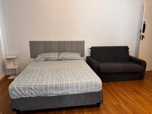 a bed and a chair in a room at 100 metros da praia do forte in Cabo Frio