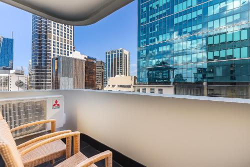 a balcony with two chairs and a view of a city at Quest on Queen Serviced Apartments in Auckland