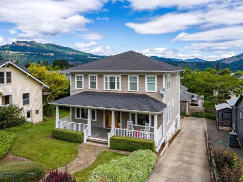 ein weißes Haus mit einer Veranda und Bergen im Hintergrund in der Unterkunft Lincoln House home in Hood River