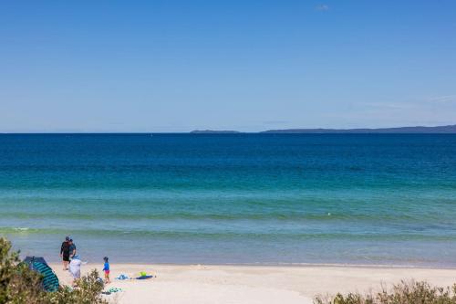 a group of people walking on the beach at Callala Beach Walk - Beachfront with Fireplace in Callala Beach