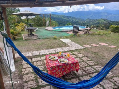 a blue hammock with a table and a pool at Eco Ortalis Cabañas in Estación El Salto