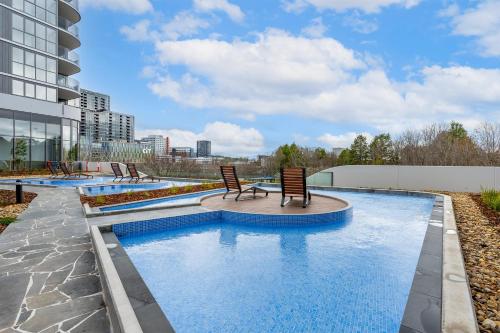a pool with two chairs in a building at Central Woden Stay, Near Hospital, CIT, Pool in Phillip