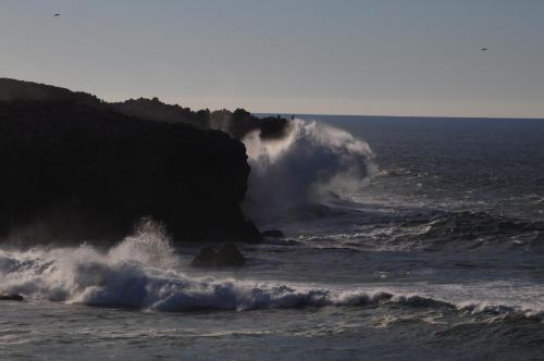 a wave crashing on a cliff in the ocean at Carrapateiramar Guest House in Carrapateira