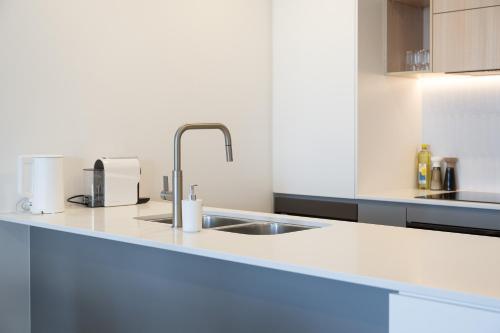 a kitchen with a sink and a counter top at Stylish Woden Apt Near Hospital w Pool, Parking in Phillip