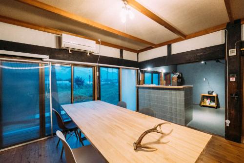 a dining room with a wooden table and chairs at hinatabocco guesthouse in Miyaki