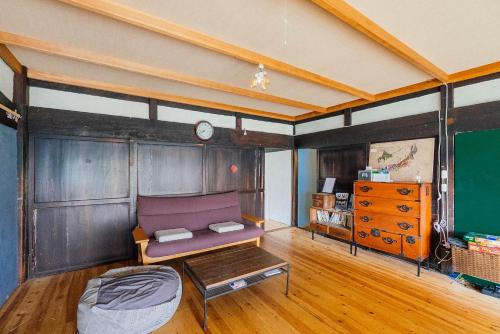 a living room with a purple couch and a table at hinatabocco guesthouse in Miyaki