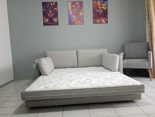 Una cama en una habitación con una silla y dos cuadros. en Capão Novo 111, en Capão da Canoa