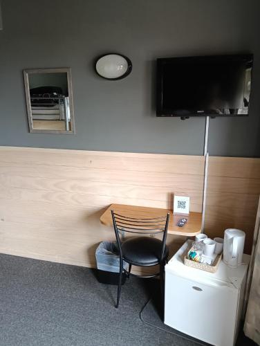 a room with a desk with a chair and a tv at Waitomo Village Chalets home of Kiwipaka in Waitomo Caves