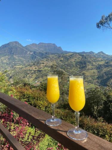 two glasses of orange juice sitting on a wooden bench at TsiaBie Hotel in Choachí