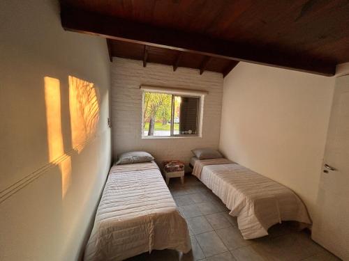 zwei Betten in einem Zimmer mit Fenster in der Unterkunft Casa Barrio Los Sauces in Chascomús