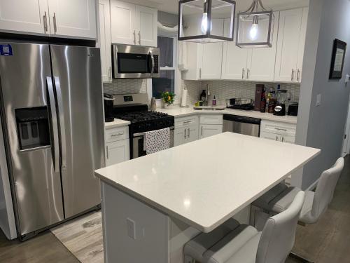 a kitchen with white cabinets and a stainless steel refrigerator at Davids Family Home in Bay Shore