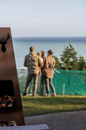 three people standing near a fence looking at the ocean at Expansive Ocean & Mountain Views - KK82140 in Kaikoura