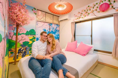 a man and woman sitting on a bed in a room at LEON RESORT HOTEL A 3rooms MAX8people 6min Shinjuku 11min Shibuya 12min walk Ikebukuro LEON RESORT IKEBUKURO traditional Japanese room 池袋 最大8名 in Tokyo