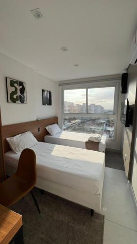 two beds in a room with a large window at Apartamento top em Vila Velha in Vila Velha