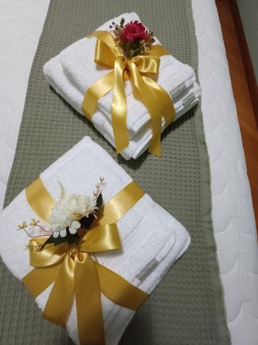 two towels with yellow bows and flowers on a bed at Casa no Centro de Pomerode - Pousada in Pomerode