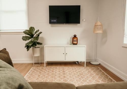 a living room with a white cabinet and a tv on the wall at Salt Cottage in Port Fairy