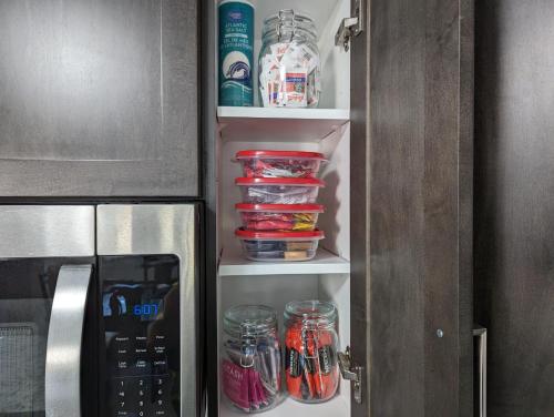 an open refrigerator door with jars and a microwave at Escape to Niagara 6 bedrooms, 5 baths with a game room, arcades in Thorold