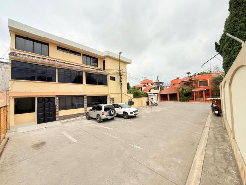 two cars parked in a parking lot in front of a building at Sol y Confort Suites in Machala