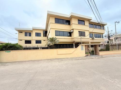 a yellow building with a fence in front of it at Sol y Confort Suites in Machala