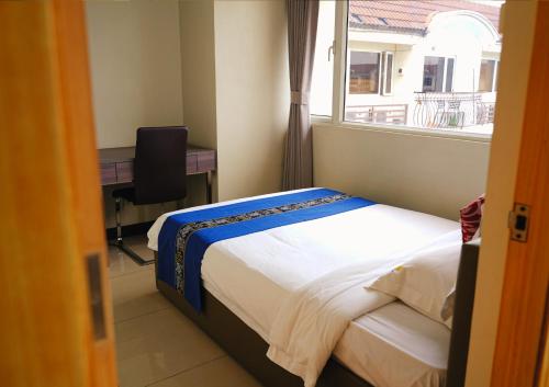 a bedroom with a bed and a desk and a window at Extremeli Suites in Manila