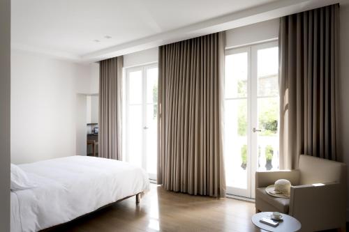 a bedroom with a bed and a chair and a window at Château Autignac in Autignac