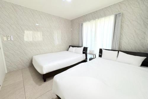 a hotel room with two beds and a window at グランディオーソ沖縄ヴィラ恩納3 in Onna