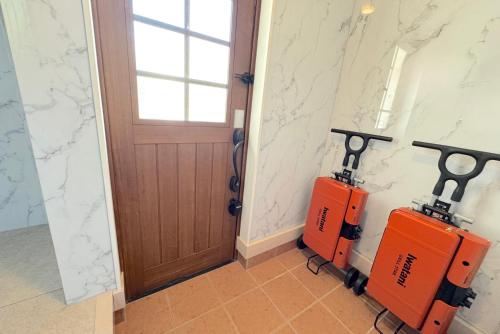 a corridor with a door and two orange machines at グランディオーソ沖縄ヴィラ恩納3 in Onna
