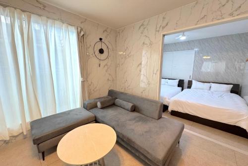 a bedroom with a bed and a couch and a table at グランディオーソ沖縄ヴィラ恩納3 in Onna