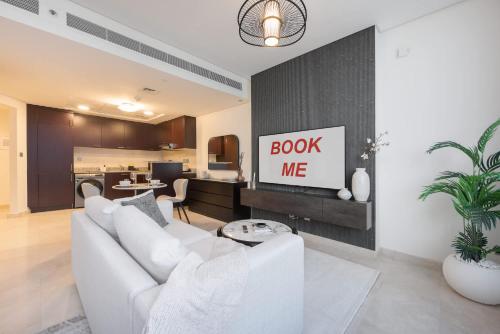 a living room with a white couch and a kitchen at Free housekeeping visits during your stay - StayShort - Extravagant Studio in DIFC with Skyline Views in Dubai