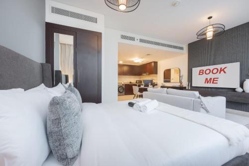 a bedroom with a white bed with a book me sign on the wall at Free housekeeping visits during your stay - StayShort - Extravagant Studio in DIFC with Skyline Views in Dubai
