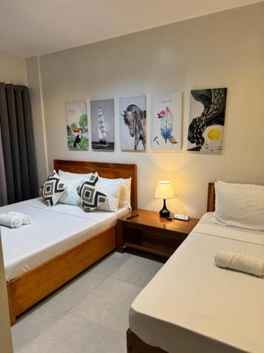 two beds in a room with pictures on the wall at Lakandiwa Tourist Inn in El Nido