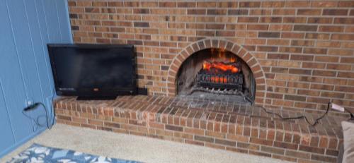 a brick fireplace with a television on top of it at Tiki Bar in The Basement in Arvada