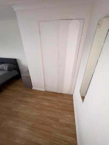 Cette chambre est dotée de murs blancs et de parquet. dans l'établissement Cosy room 3 Gatwick, à Crawley