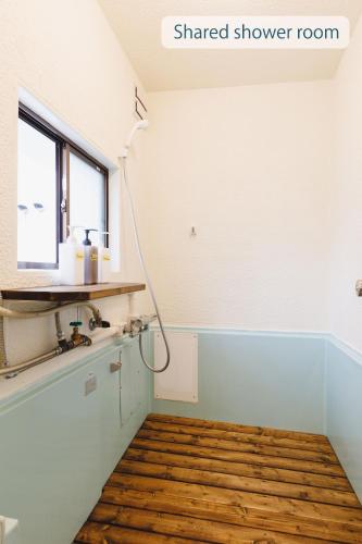 a room with a shaded shower room with a wooden floor at Couch Potato Hostel in Matsumoto