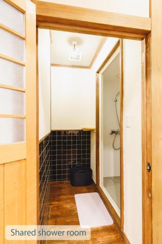 a bathroom with a mirror and a black tiled shower room at Couch Potato Hostel in Matsumoto
