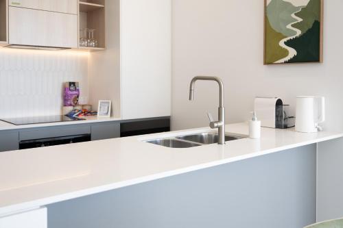 a white kitchen with a sink and a counter at Sunny Central Woden Apt,Hospital, CIT , Pool in Phillip