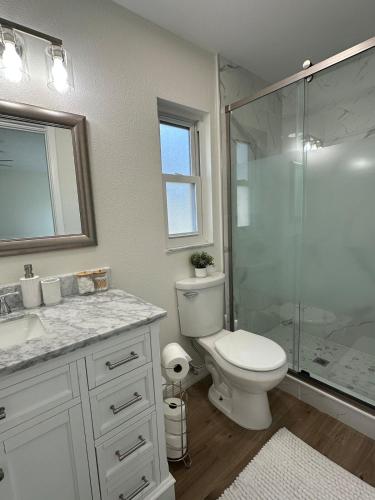 a bathroom with a toilet and a glass shower at CASA SOLÉ, South Tampa in Tampa