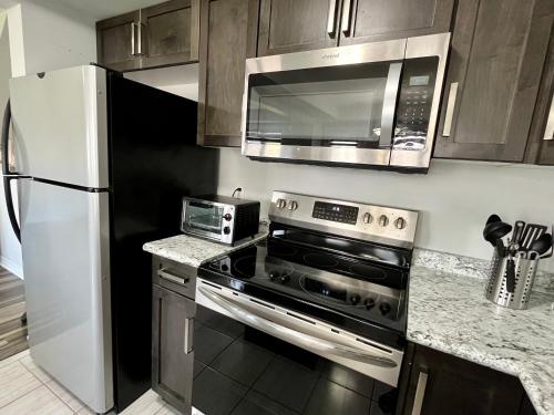 a kitchen with a stove and a microwave and a refrigerator at Escape to Niagara 6 bedrooms, 5 baths with a game room, arcades in Thorold