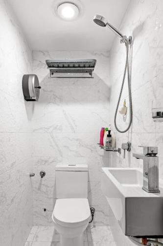 a white bathroom with a toilet and a sink at Spacious King Studio Room in Carramar - Nearby Station & Shops - Shared Bathroom and Kitchen in Villawood