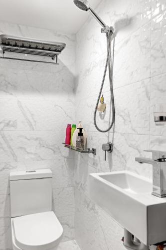 a white bathroom with a toilet and a sink at Spacious King Studio Room in Carramar - Nearby Station & Shops - Shared Bathroom and Kitchen in Villawood
