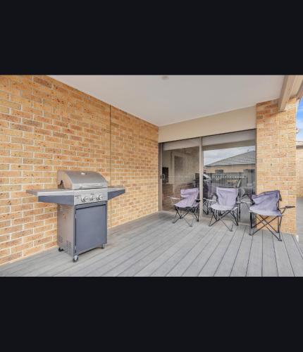 a patio with a grill and chairs on a deck at Comfort Heaven in Craigieburn