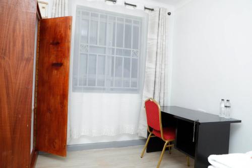 a black desk with a red chair next to a window at Modern Guest House 2BR in Nakuru