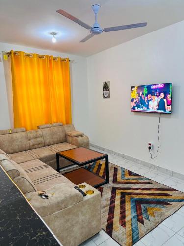 Una sala de estar con un sofá y un televisor en la pared. en Home by Mercy Apiyo, en Mombasa
