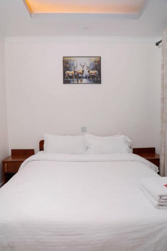 a white bed in a bedroom with a picture on the wall at Modern Guest House 2BR in Nakuru