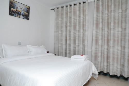 a bedroom with a white bed and a window at Modern Guest House 2BR in Nakuru