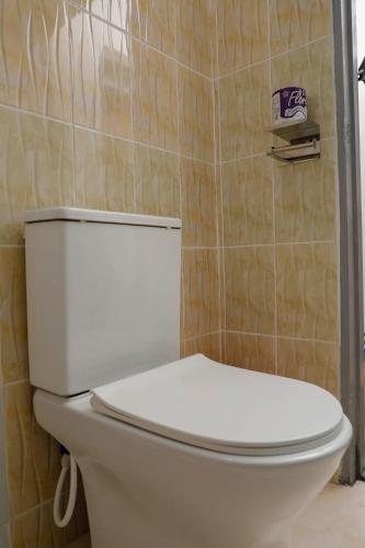 a white toilet in a bathroom with a tiled wall at Modern Guest House 2BR in Nakuru